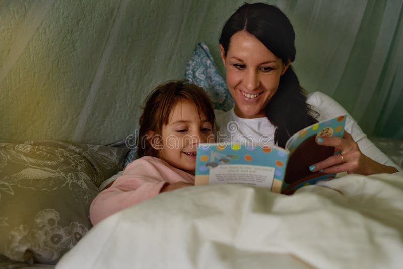 Mère fille et livre d'histoire dans l'apprentissage du lit et la littérature pour le coucher et se détendre à la maison. fille mam photos stock