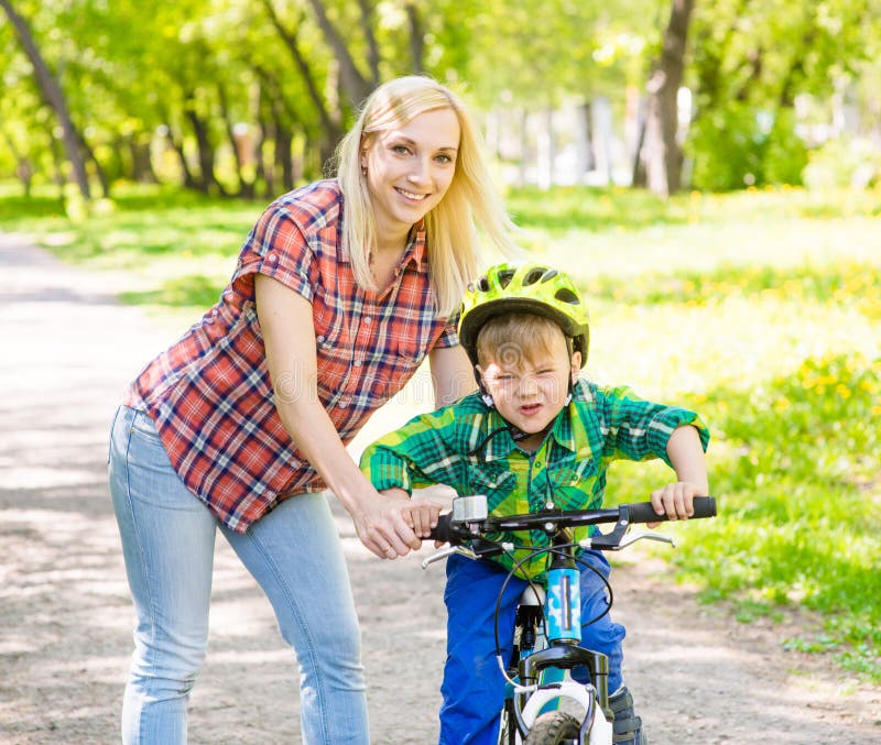 Mère heureuse avec son fils ayant l'amusement, montant une bicyclette photographie stock Mère heureuse avec son fils ayant l'amusement, montant une bicyclette photographie stock