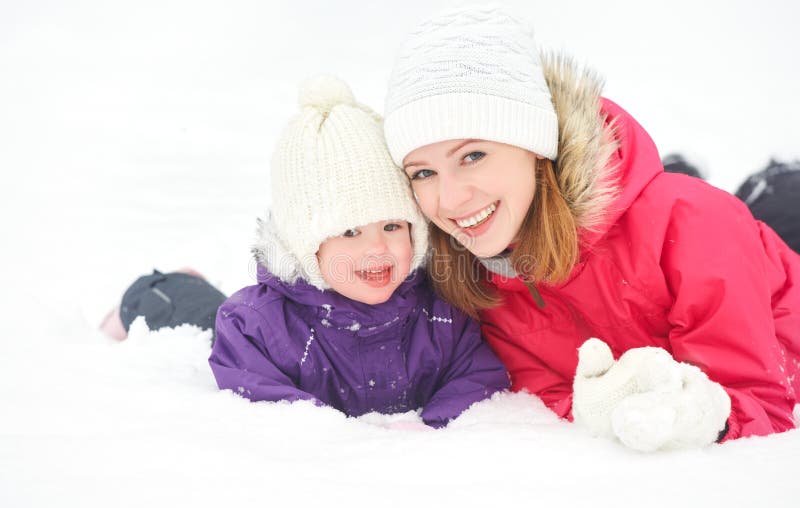 Mère heureuse de famille et fille de bébé jouant et riant dans la neige d'hiver images libres de droits Mère heureuse de famille et fille de bébé jouant et riant dans la neige d'hiver images libres de droits