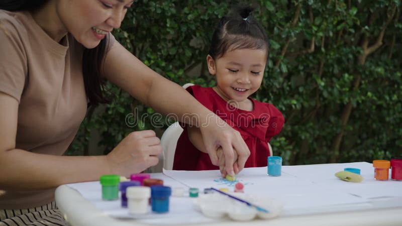 Mère heureuse et petite fille peignant de l'aquarelle à partir d'un bananier en papier dans le jardin. banque de vidéos