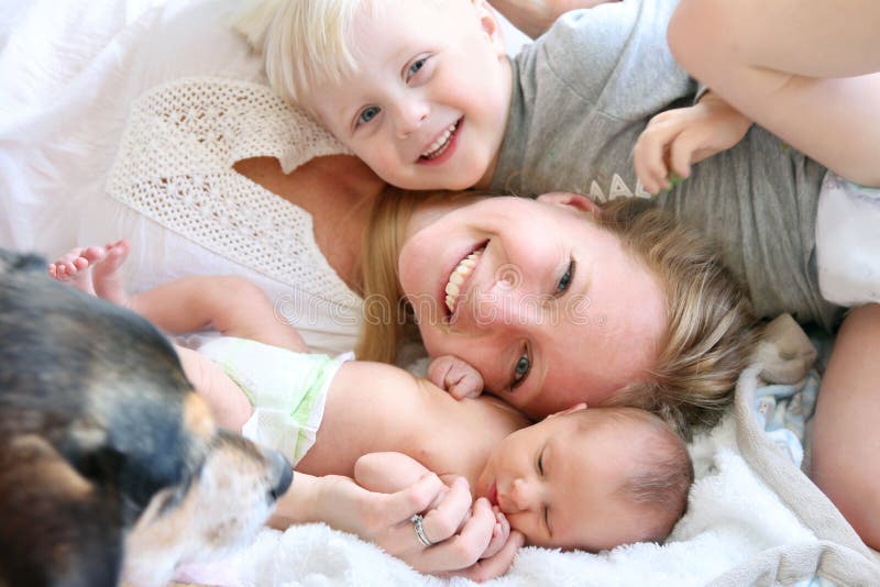 Mère heureuse s'étendant dans le lit avec le fils d'enfant en bas âge et le bébé nouveau-né photo libre de droits Mère heureuse s'étendant dans le lit avec le fils d'enfant en bas âge et le bébé nouveau-né photo libre de droits