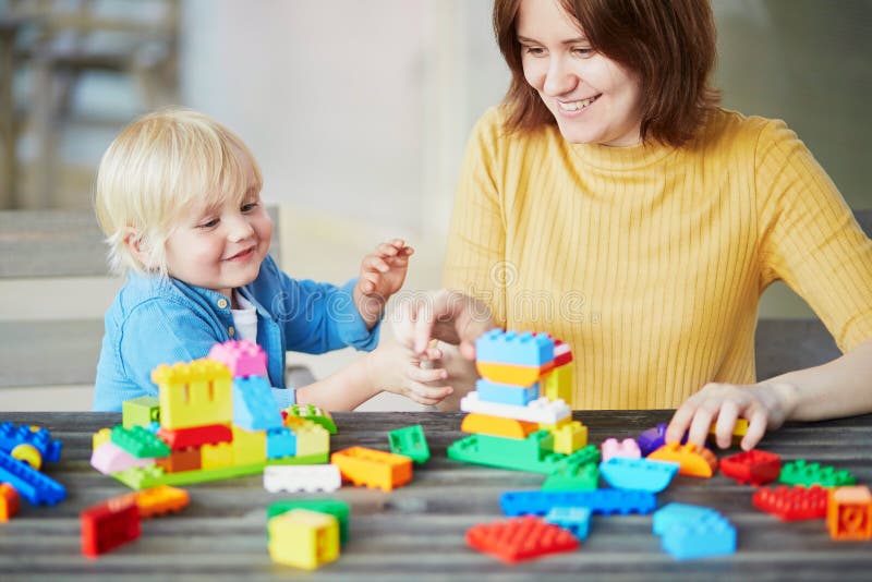 Mère jouant les blocs colorés de construction avec son fils photographie stock libre de droits Mère jouant les blocs colorés de construction avec son fils photographie stock libre de droits