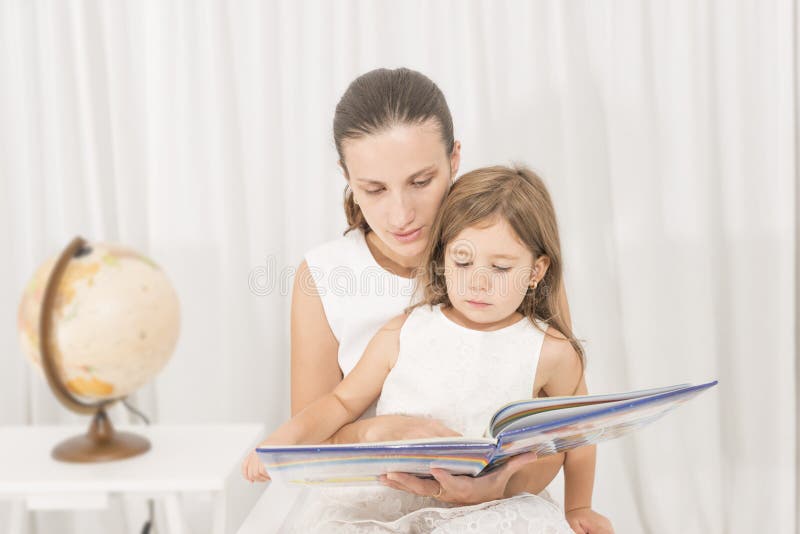 Mère lisant un livre à son enfant image stock Mère lisant un livre à son enfant image stock