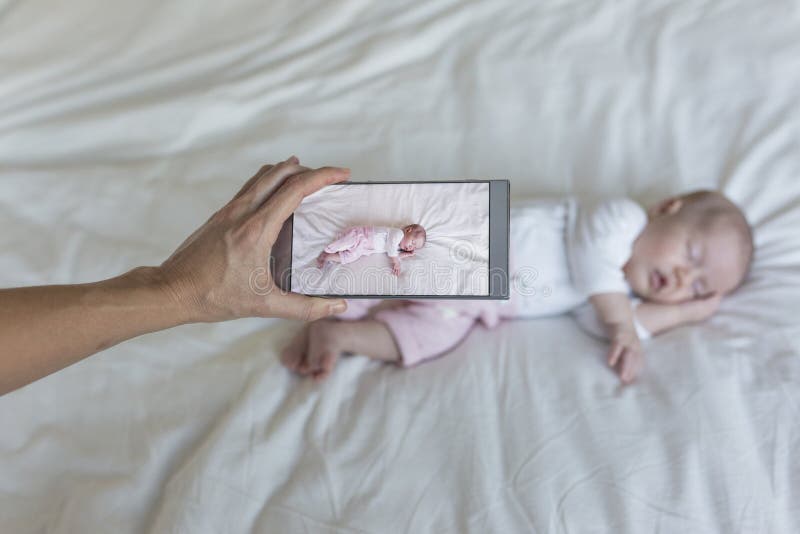 mère prenant une photo de son bébé dormant sur le lit Famille et concept d'amour photographie stock mère prenant une photo de son bébé dormant sur le lit Famille et concept d'amour photographie stock