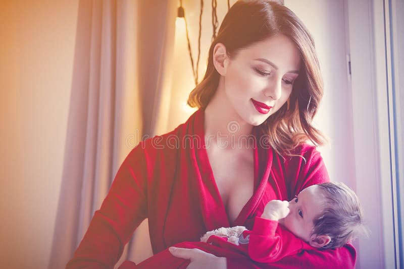 Mère rousse avec l'enfant nouveau-né en rouge images libres de droits Mère rousse avec l'enfant nouveau-né en rouge images libres de droits