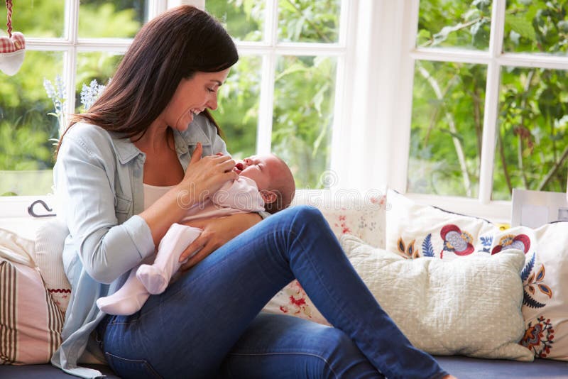 Mère à la maison caressant le bébé nouveau-né à la maison images stock Mère à la maison caressant le bébé nouveau-né à la maison images stock