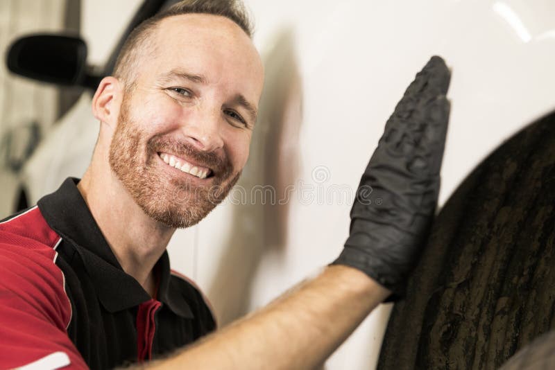 Mécanicien beau basé sur la voiture dans l'atelier de réparations automatiques photo stock Mécanicien beau basé sur la voiture dans l'atelier de réparations automatiques photo stock