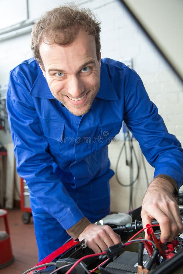 Car mechanic repairing a automobile in a garage or workshop. Car mechanic repairing a automobile in a garage or workshop