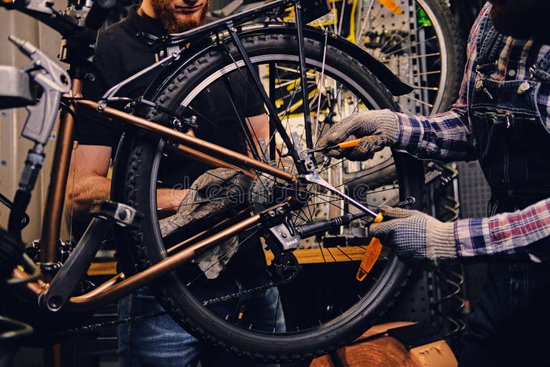 Mécanicien fixant le dérailleur arrière d'une bicyclette photo stock