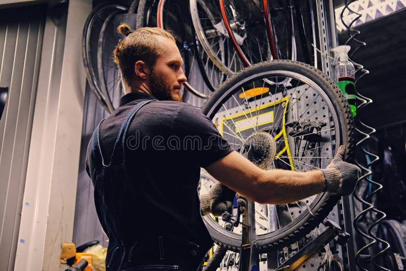 Mécanicien réparant le pneu de roue de bicyclette dans un atelier photo stock