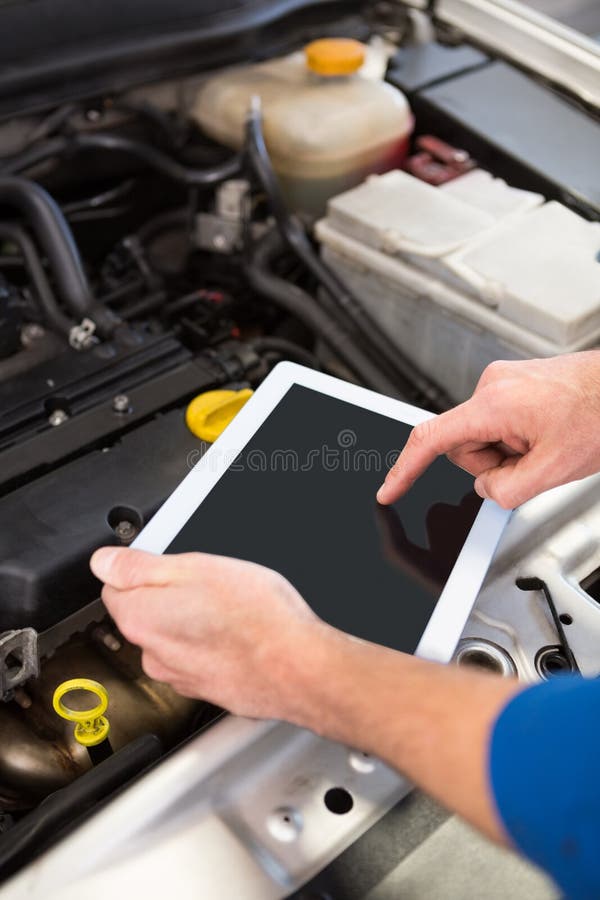 Mécanicien à l'aide du comprimé pour fixer la voiture photo libre de droits Mécanicien à l'aide du comprimé pour fixer la voiture photo libre de droits
