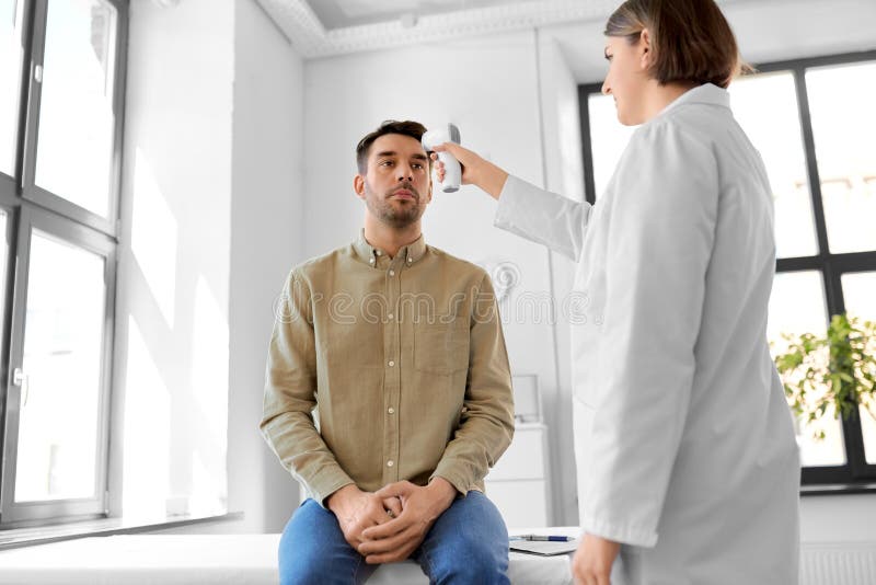 Médecin avec thermomètre et homme à l'hôpital image libre de droits
