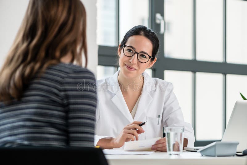 Médecin féminin écoutant son patient pendant la consultation image stock Médecin féminin écoutant son patient pendant la consultation image stock