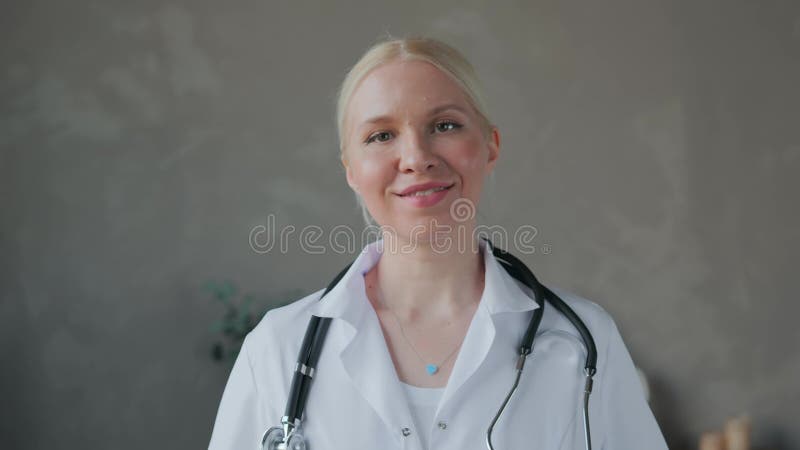 Médecin une jeune femme en manteau blanc regarde la caméra