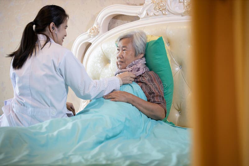 Médica de família ou enfermeira verificando coração e pulmões de paciente sênior usando estetoscópio na cama em casa,cuidadora as fotos de stock royalty free Médica de família ou enfermeira verificando coração e pulmões de paciente sênior usando estetoscópio na cama em casa,cuidadora as fotos de stock royalty free