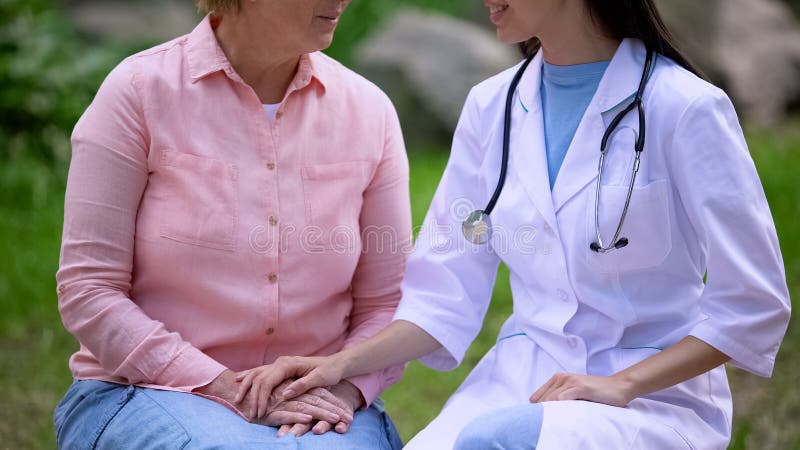Médica que reconforta pacientes idosos no jardim hospitalar, serviço médico imagens de stock Médica que reconforta pacientes idosos no jardim hospitalar, serviço médico imagens de stock