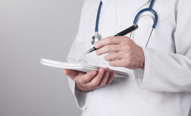 Médico caucasiano escreve no bloco de notas foto de stock