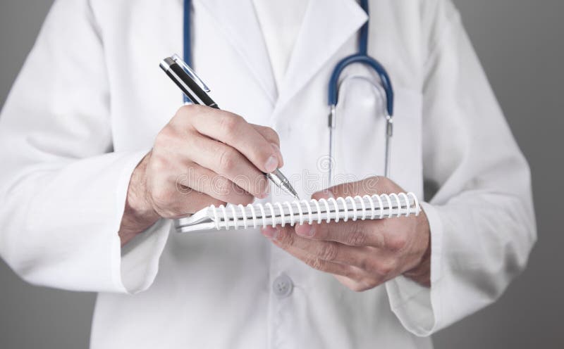 Médico caucasiano escreve num bloco de notas imagens de stock royalty free