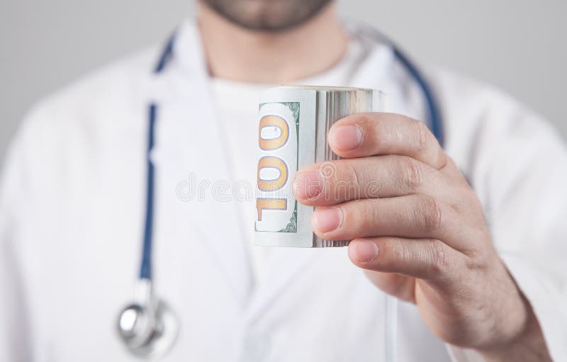 Médico caucasiano a mostrar notas de dólar fotografia de stock royalty free