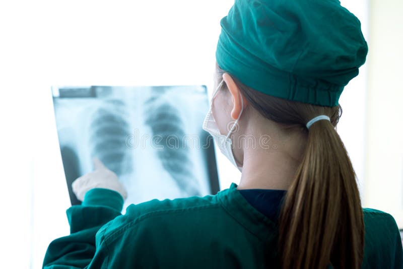 Médico das mulheres fêmeas que olha raios X em um hospital verificando o filme do raio da caixa x na divisão fotos de stock Médico das mulheres fêmeas que olha raios X em um hospital verificando o filme do raio da caixa x na divisão fotos de stock
