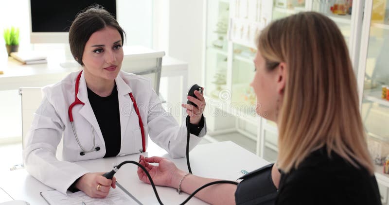 Médico do sexo feminino mede a pressão arterial do doente na clínica