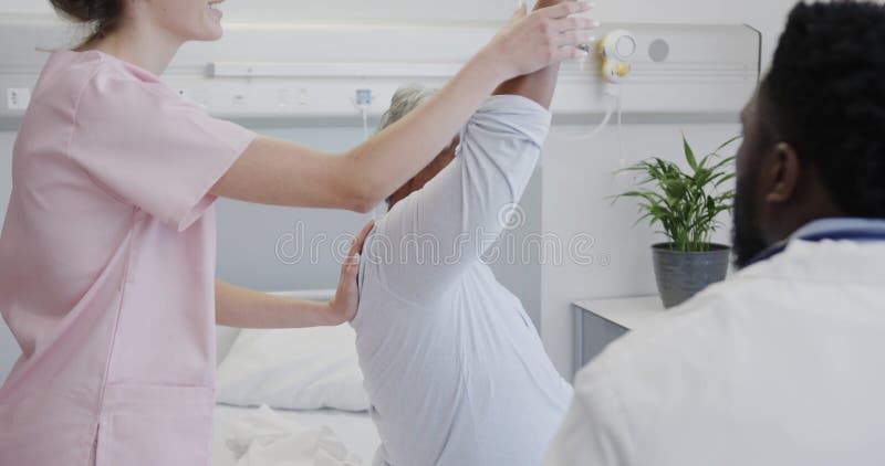 Médico masculino diverso y fisiofísico femenino tratando a pacientes de edad avanzada cámara lenta almacen de metraje de vídeo