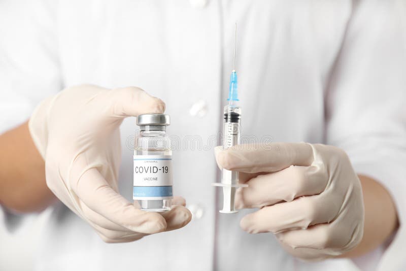 Médico sujetando el vial con la vacuna y la jeringa contra covid19 closeup