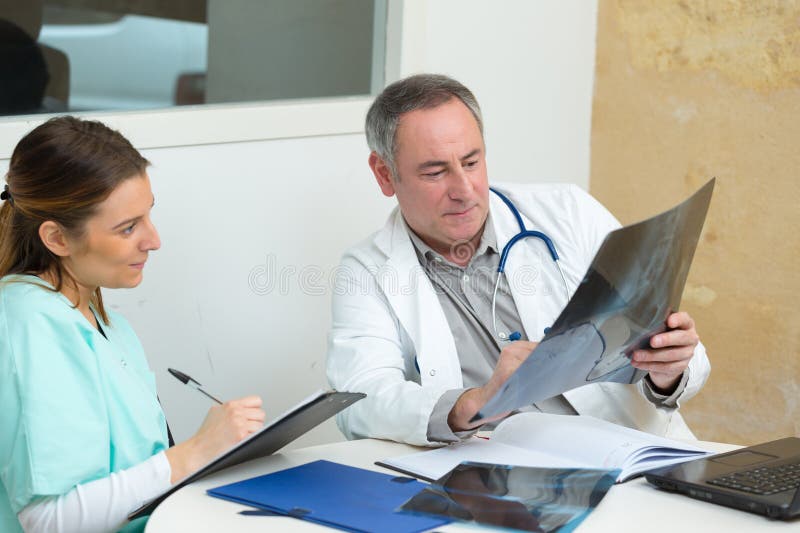 Médico y enfermero en el consultorio que trabaja en un informe médico fotos de archivo