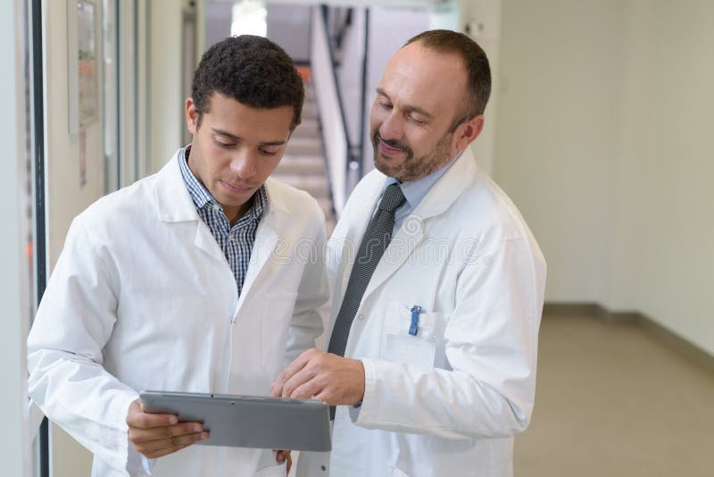 Médicos de mayor edad y de menor edad que consultan el tablet pc fotografía de archivo