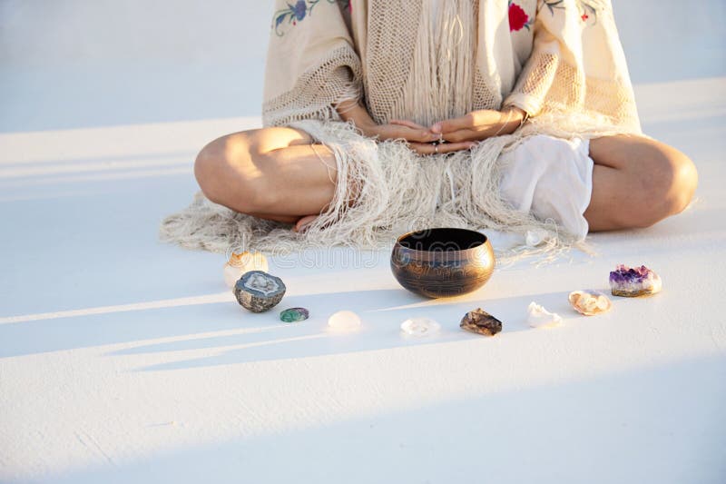 Close up detail of a woman with her hands in meditation before a Tibetan Singing Bowl and an array of crystals. Close up detail of a woman with her hands in meditation before a Tibetan Singing Bowl and an array of crystals.