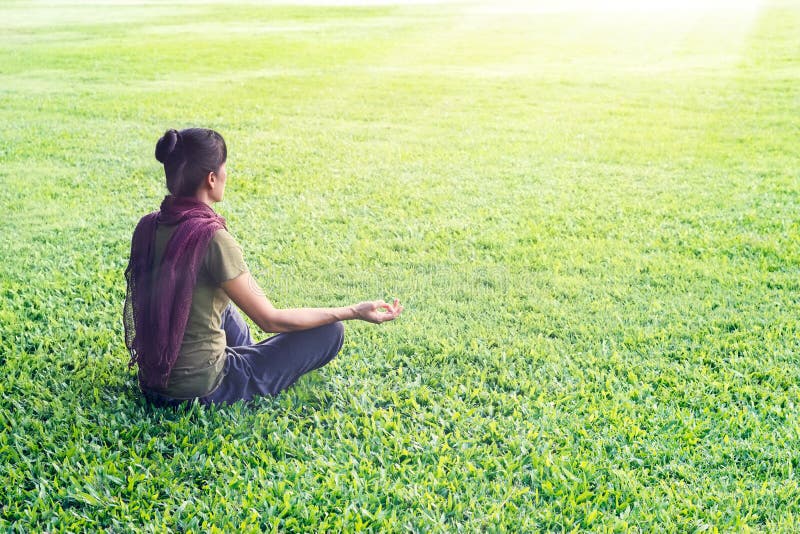 Méditer de femme de yoga extérieur en parc sur le fond de champ d'herbe photographie stock libre de droits Méditer de femme de yoga extérieur en parc sur le fond de champ d'herbe photographie stock libre de droits