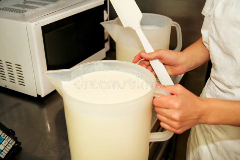 Mélange d'ingrédients de crème glacée ainsi que le mélangeur Le chef féminin mélange le lait et prépare des fondements pour la pr photographie stock Mélange d'ingrédients de crème glacée ainsi que le mélangeur Le chef féminin mélange le lait et prépare des fondements pour la pr photographie stock