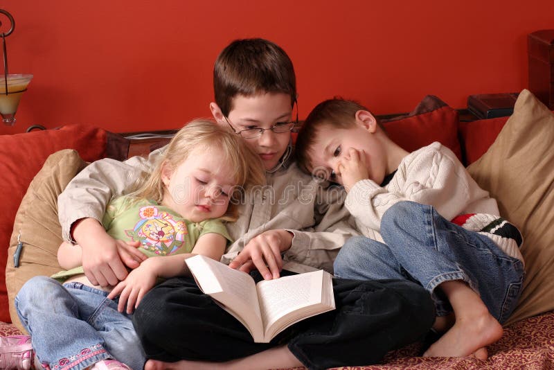 3 children at home reading a book together. 3 children at home reading a book together