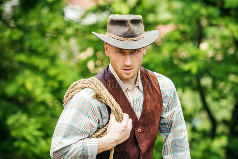 Mönster i västlig stil Handsome cowboy i en plaid-skjorta med vacker bakgrund på landsbygden Sexuellt manligt snylt royaltyfri foto