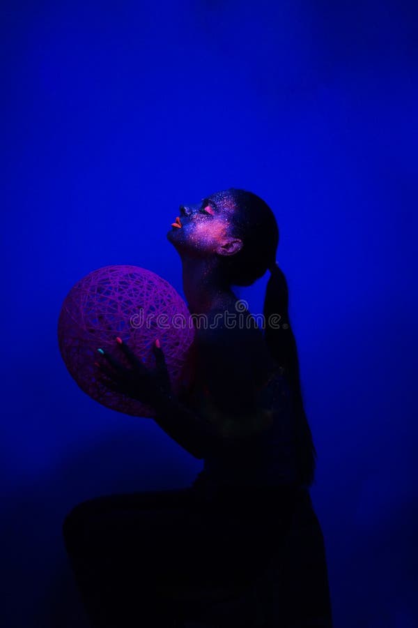 Mörker för flickasammanträdeprofil under UV ljus med bollen royaltyfria foton Mörker för flickasammanträdeprofil under UV ljus med bollen royaltyfria foton