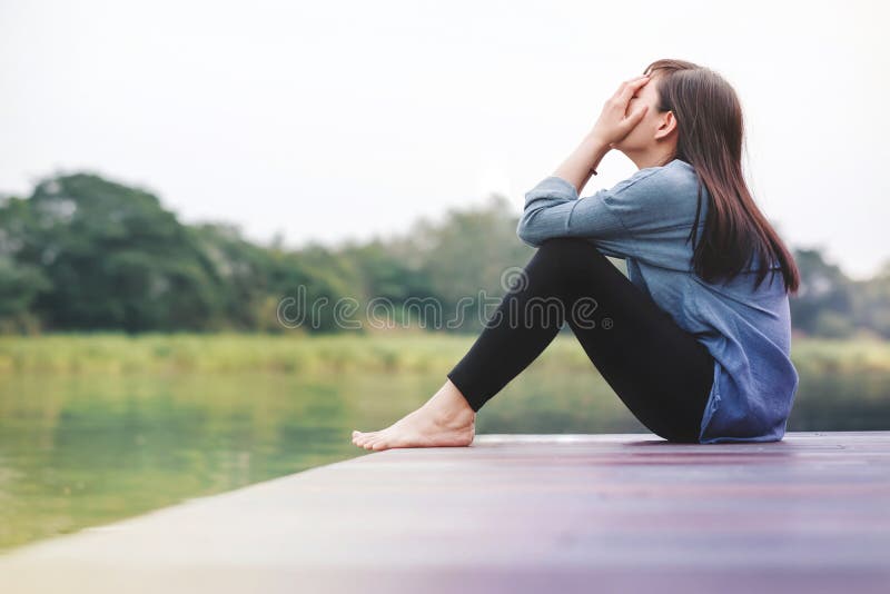 Mún concepto del día Mujer de la tristeza que se sienta por el río fotografía de archivo Mún concepto del día Mujer de la tristeza que se sienta por el río fotografía de archivo