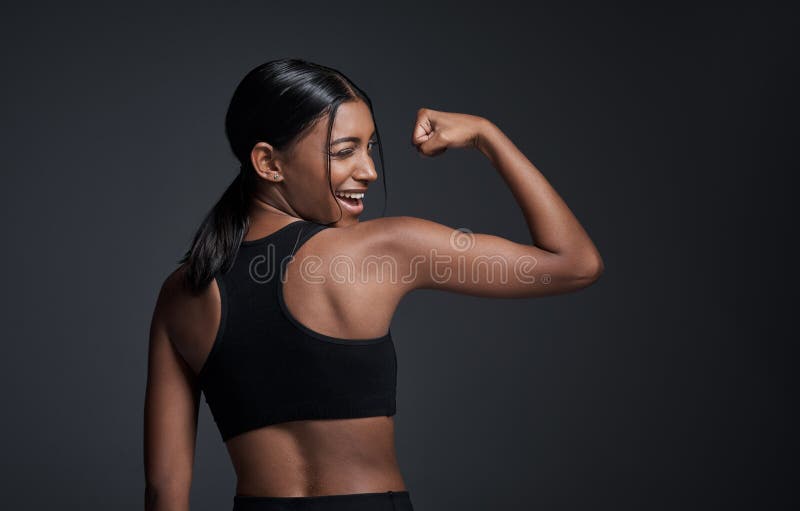Músculo espumoso de guiño feliz y mujer en un estudio aislado en una burla de fondo negro. fuerte flex divertido e indio. atleta hembra hindú y flex fuerte con fuerza de brazo bicep o retroactividad de culturista.