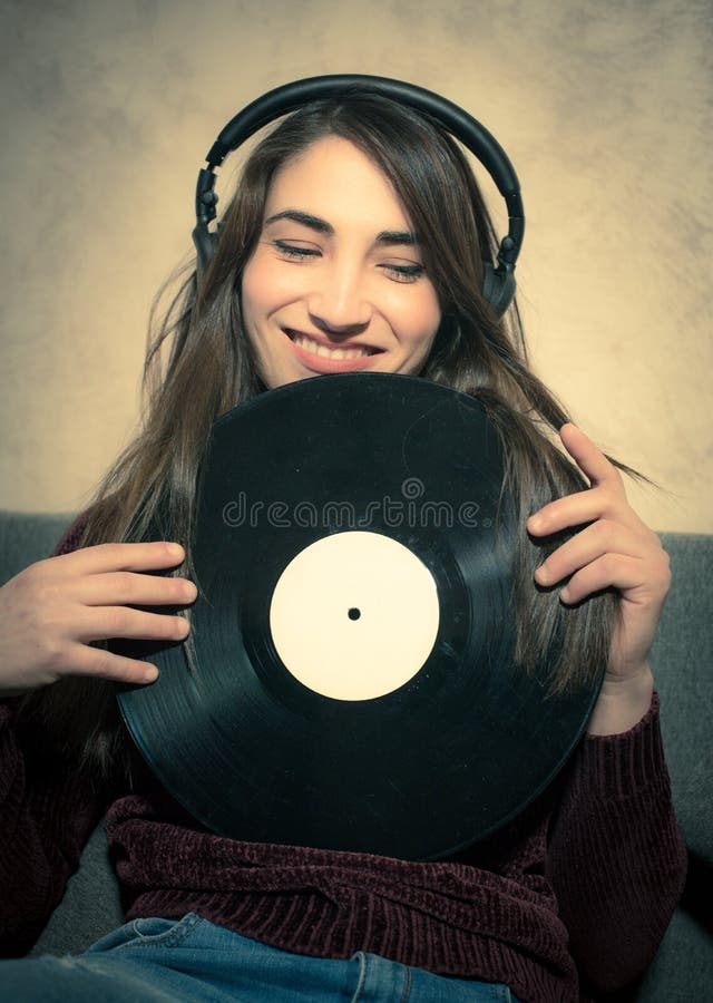 Música de escuta de sorriso nova da mulher com registros de vinil fotografia de stock royalty free Música de escuta de sorriso nova da mulher com registros de vinil fotografia de stock royalty free