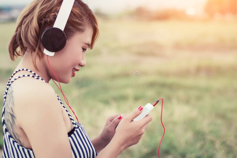 Música de respiração e de escuta da mulher 'sexy' relaxado de um smartpho imagens de stock Música de respiração e de escuta da mulher 'sexy' relaxado de um smartpho imagens de stock