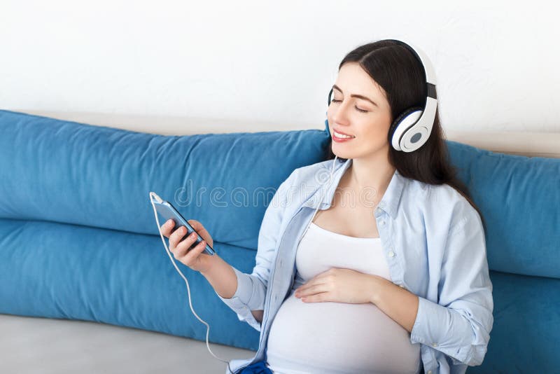 Música que escucha de la mujer embarazada en auriculares fotos de archivo libres de regalías Música que escucha de la mujer embarazada en auriculares fotos de archivo libres de regalías