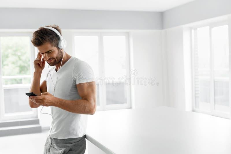 Música que escucha Hombre en auriculares usando el teléfono móvil dentro