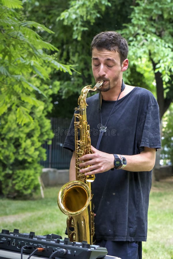 Músico joven que realiza música de la calle en el saxofón fotos de archivo Músico joven que realiza música de la calle en el saxofón fotos de archivo