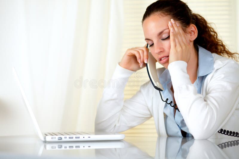 Müde Frau mit den Kopfschmerzen, die am Telefon sprechen