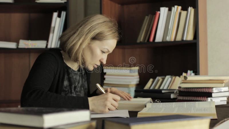 Müde Studentenvorbereitungsselbstverständlich Arbeit in einer Bibliothek im College, bereitend für Prüfungen vor