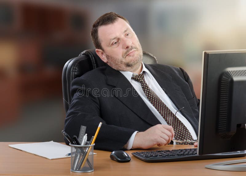 Müder Geschäftsmann betrachtet Computer stockbild Müder Geschäftsmann betrachtet Computer stockbild