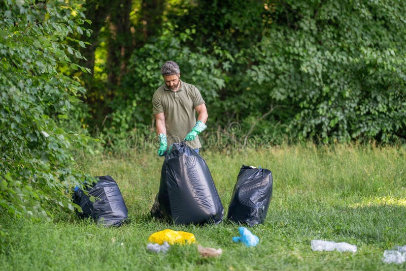 Müllabfuhr im Wald. Ökokonzept. Freiwilliger Müllsammler. Mann in Gummihandschuhen mit Müllbeutel sauber stockfoto