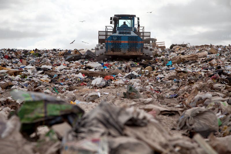 Garbage piles up in landfill site each day while truck covers it with sand for sanitary purpose. Garbage piles up in landfill site each day while truck covers it with sand for sanitary purpose