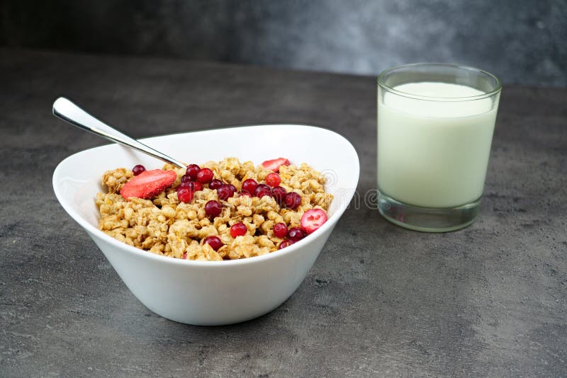 Müsli mit Srawbeere und Cranberry mit Glas Jogurt in weißer Schüssel auf grauem Hintergrund stockfotos
