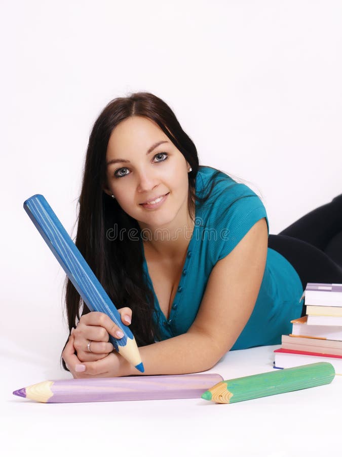 Smart young woman holding big pencil lying on the floor, studio portrait. Smart young woman holding big pencil lying on the floor, studio portrait