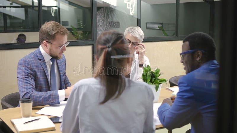 Mądrze wieloetniczna grupa opowiada początkowego projekt przy biurkiem w oświetleniowym pokoju